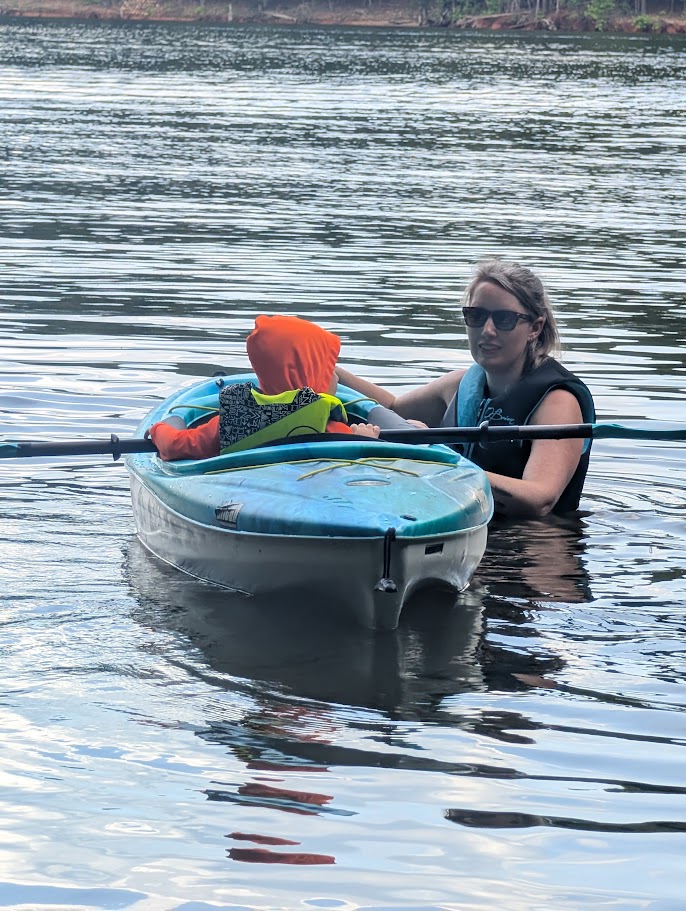 Emily Anderson helps her child navigate a kayak.